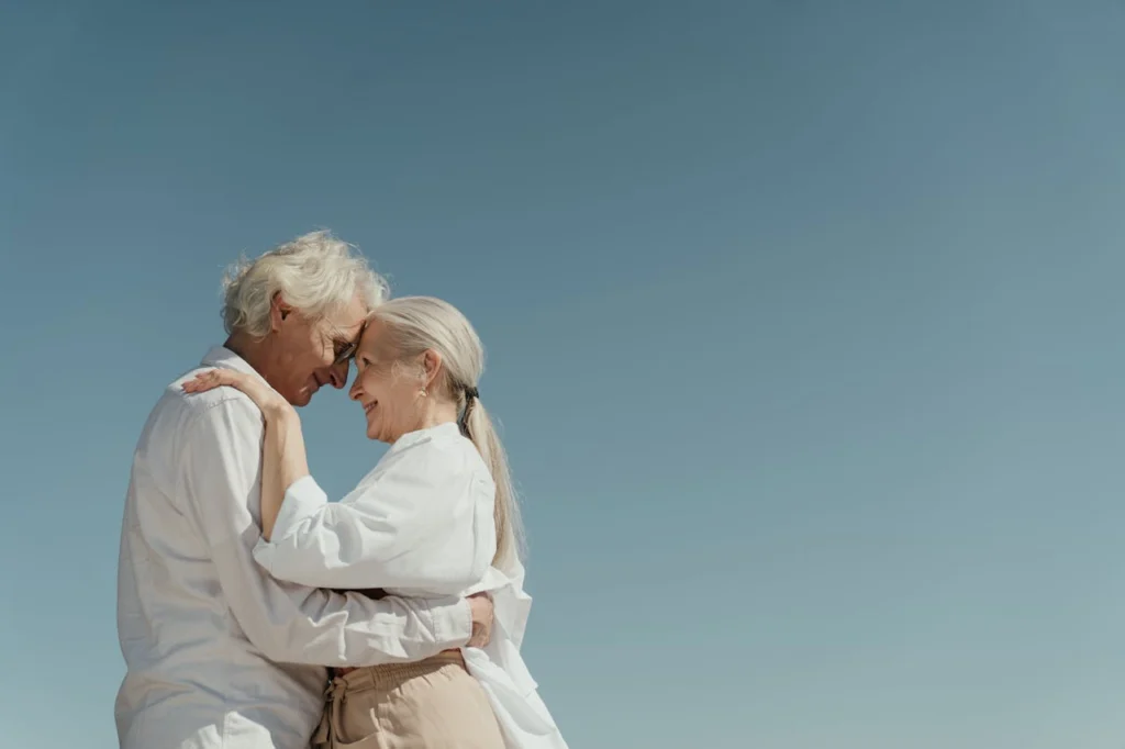In the picture, an elderly couple hugging and looking into each other's eyes.